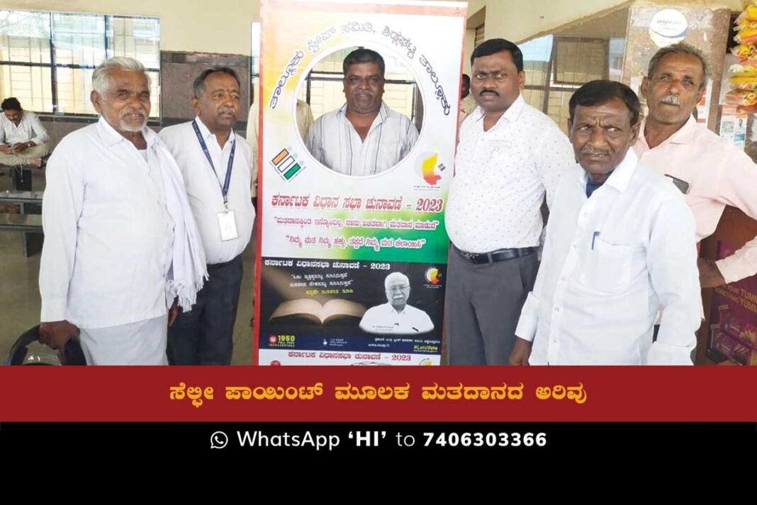 A group of people taking a selfie in front of a banner promoting the Karnataka assembly elections.